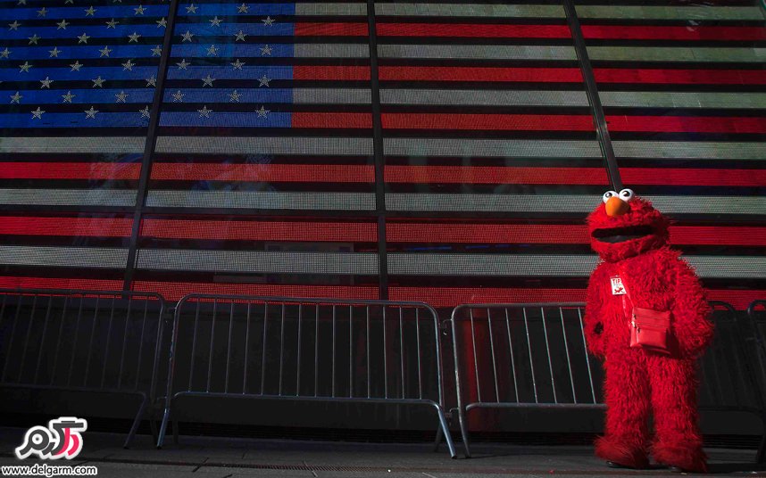 شخصیت کارتونی اِلمو در کنار پرچم آمریکا در منهتن
