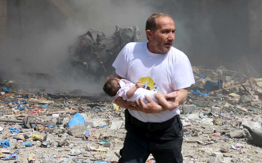 مرد سوری در حال نجات یک نوزاد پس از انفجار بمب در سوریه